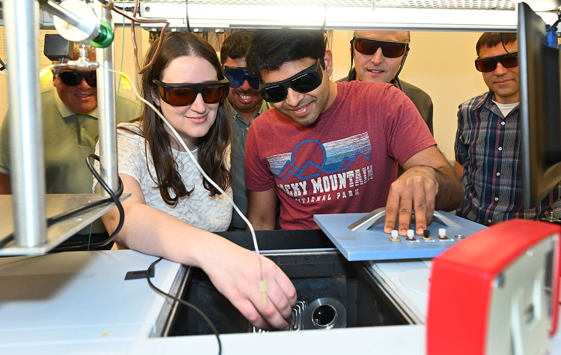 A group of researchers wearing protective glasses while they'll work with lab equipment