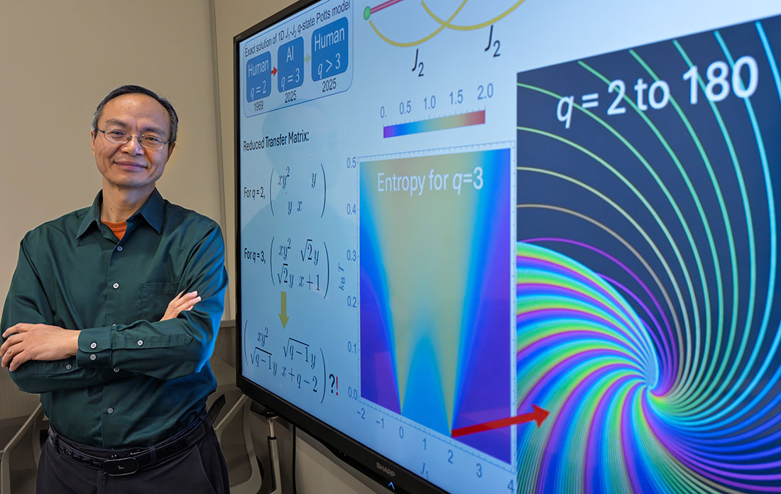 Weiguo Yin stands by a screen displaying equations used in his work