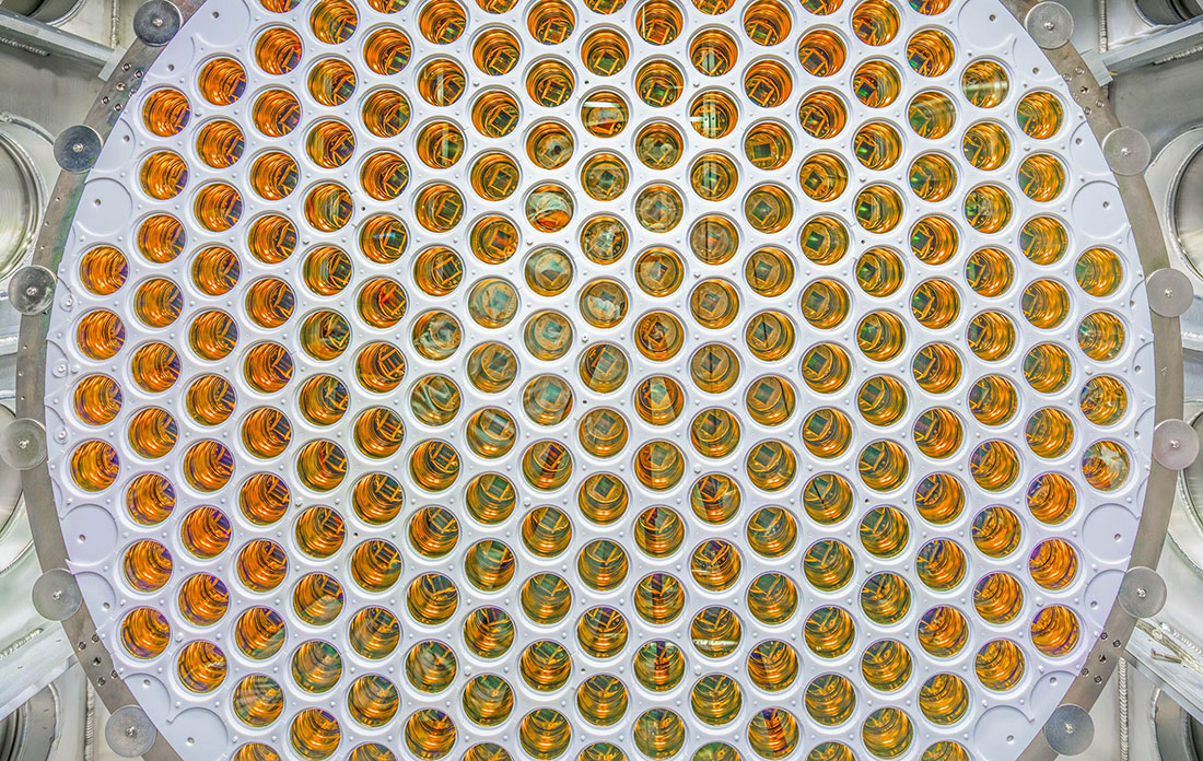 A circular array of amber, glossy photomultiplier tubes arranged in a grid pattern.