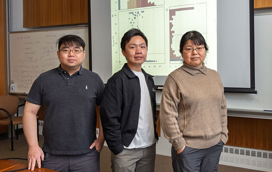 Wenjie Liao, An Nguyen, and Ping Liu stand in front of a projected data slide from a machine learnin