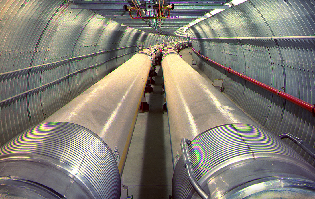 Tunnel of the Relativistic Heavy Ion Collider with parallel beam pipes extending into the distance.