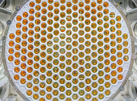 A circular array of amber, glossy photomultiplier tubes arranged in a grid pattern.