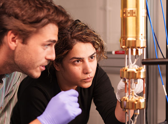 Two researcher examine a quantum device