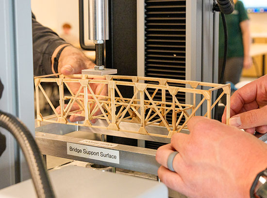 A small wooden bridge under a testing machine